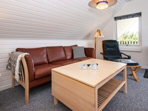 A cozy room with a brown leather sofa, a wooden coffee table, and a black leather chair.