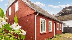 Ein rotes Haus mit weißen Fenstern und einer sichtbaren Dachrinne.