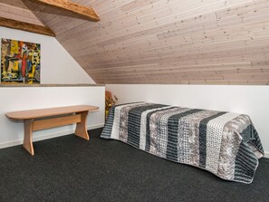 A small, cozy room with a sloped ceiling, a wooden bench, a bed with a patterned quilt, and a colorful abstract painting on the wall. - 6 Person Holiday Home in Bredebro (Bredebro)