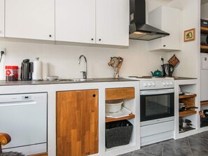 A modern kitchen with white cabinetry, a stainless steel sink, a stove, and a dishwasher.