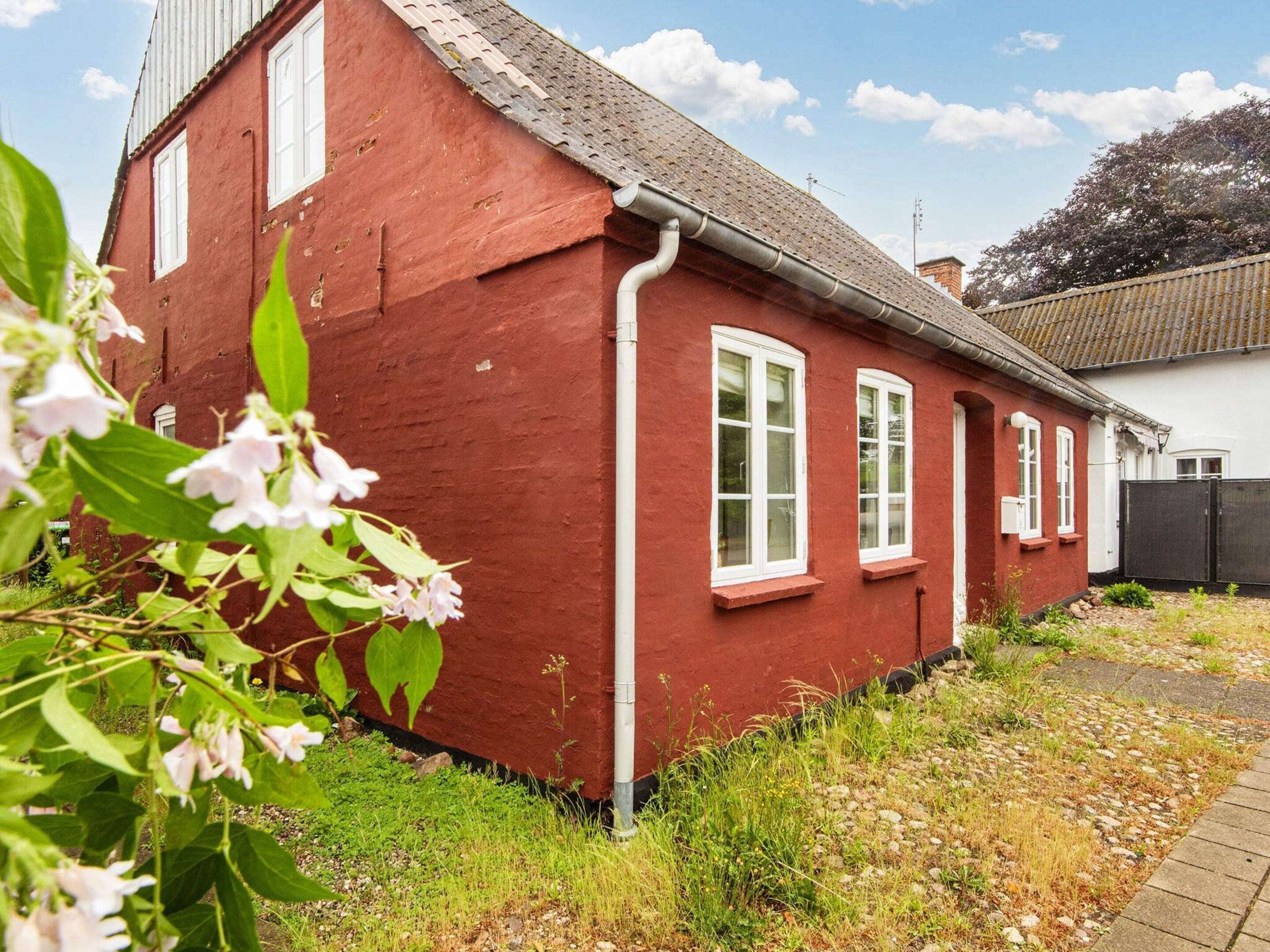 A red house with white windows and a visible gutter.