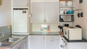 Eine kompakte Küche mit Kühlschrank, Mikrowelle, Spüle und einer kleinen Arbeitsplatte mit Toaster.