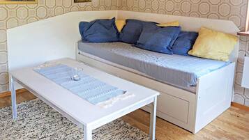 A room with a white sofa, a small table, and a patterned rug.