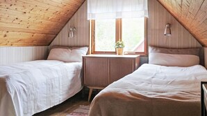 Ein gemütliches Schlafzimmer im Dachgeschoss mit zwei Betten, einem kleinen Tisch und einem Fenster mit Aussicht.