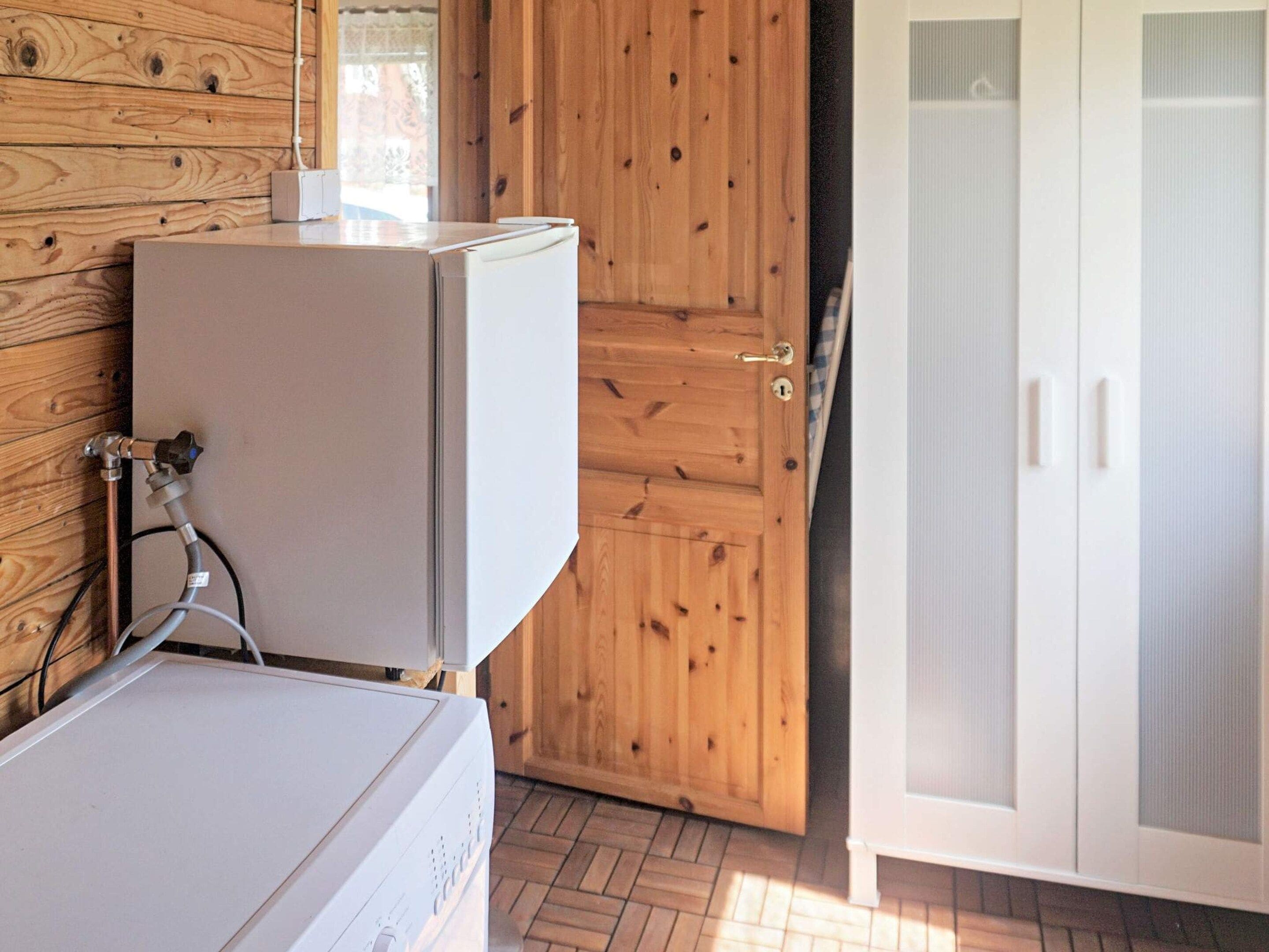 A room with a white washing machine, a wooden door, and a white cabinet with glass doors.