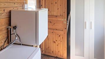A room with a white washing machine, a wooden door, and a white cabinet with glass doors.