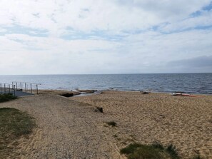 A beach with a fenced area and a path leading to the water.