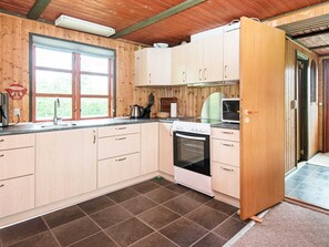 A kitchen with wooden cabinets, a stove, a sink, and a window. - 5 Person Holiday Home in Tarm (Tarm)