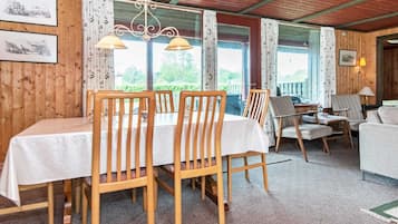 Un área de comedor con sillas de madera y una mesa, un sofá y una lámpara.