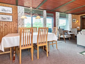 A dining area with wooden chairs and a table, a sofa, and a lamp. - 5 Person Holiday Home in Tarm (Tarm)
