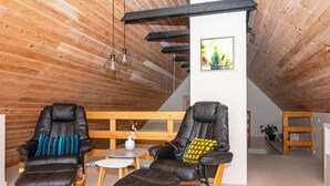A cozy room with two leather recliners, a small table, and a wooden bench. - Holiday Home in Aars (Aars)