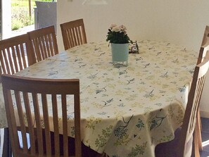 Une table à manger recouverte d’une nappe à motifs floraux, entourée de chaises en bois.