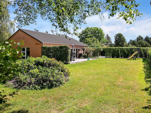 A house with a brick exterior, a covered patio, and a grassy yard.