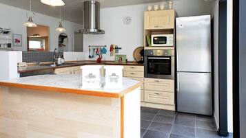 A modern kitchen with a central island, stainless steel appliances, and pendant lighting.