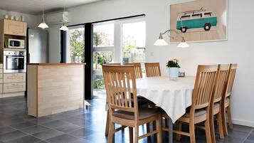 A modern kitchen with a dining area, wooden chairs, a white table, and a kitchen island.