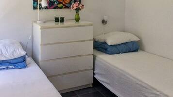 Un dormitorio pequeño y ordenado con una cama individual, un aparador y un cuadro colgado en la pared.