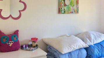 A bedroom with a bed, pillows, a dresser, a mirror, and a wall decoration.
