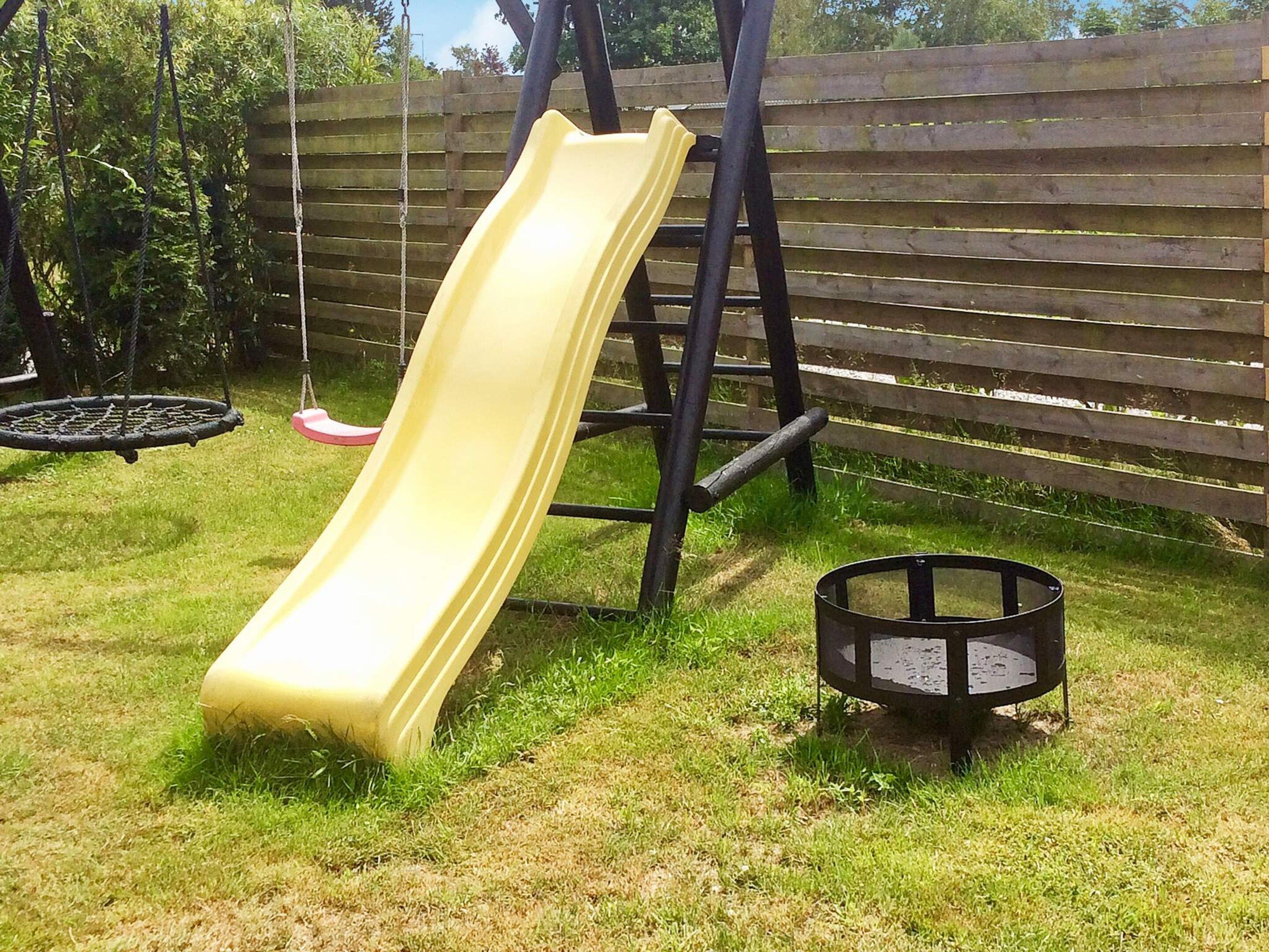 Un parque infantil con un tobogán amarillo y columpios.