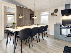 A modern kitchen with a built-in oven and a dining area with a long table and chairs.