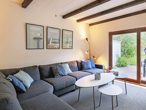 A modern living room with a sectional sofa, a round coffee table, and framed pictures on the wall.