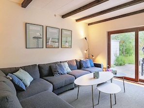 A modern living room with a sectional sofa, a small round table, and three framed pictures on the wall.