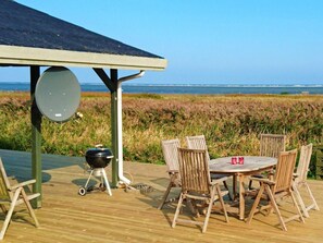 An outdoor dining area with a round table and chairs, a grill, and a view of the sea. - 6 Person Holiday Home in Hadsund (Hadsund)