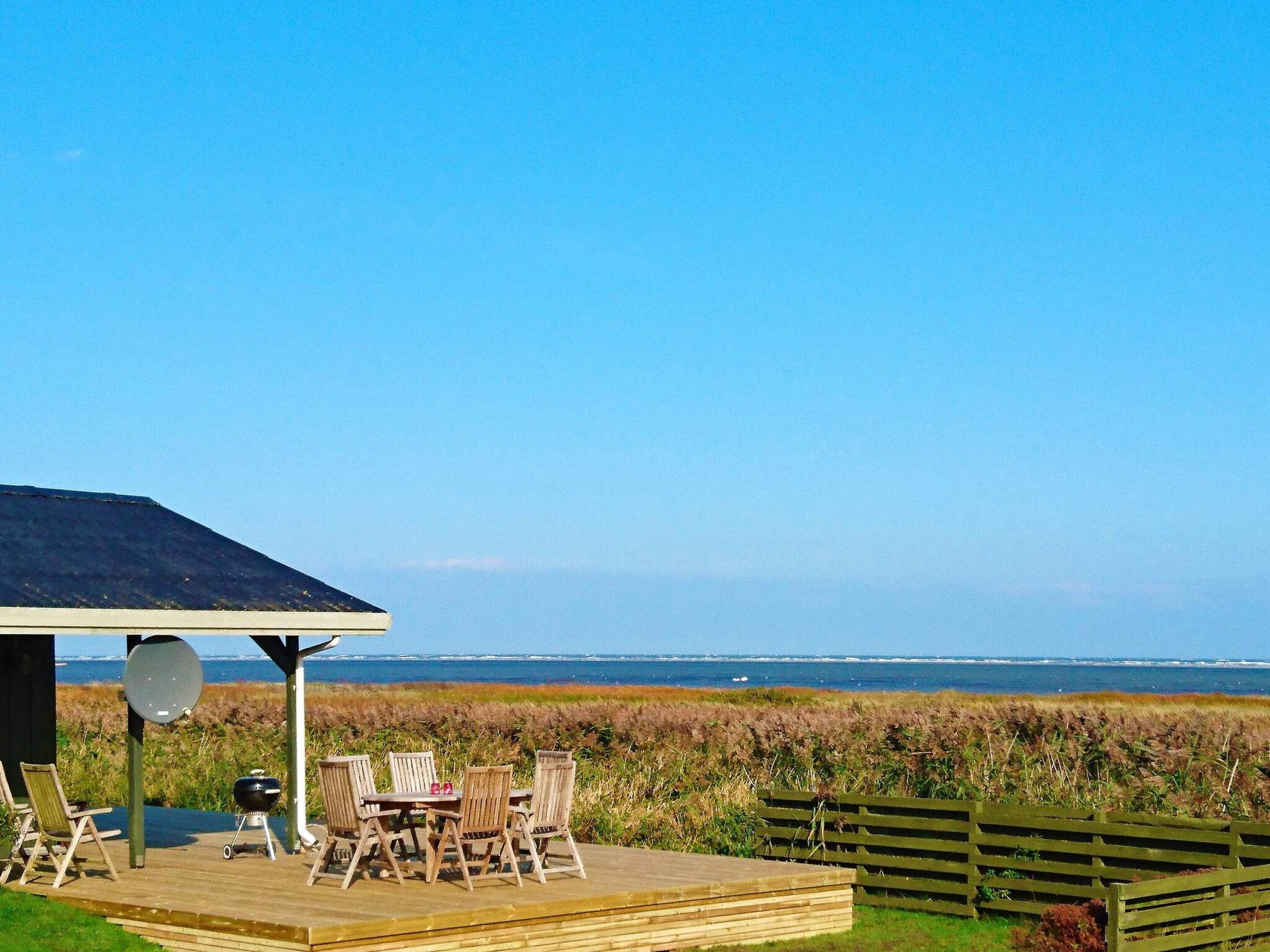 A wooden deck with outdoor furniture, a barbecue grill, and a satellite dish.