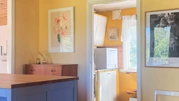 Una cocina con refrigerador, pileta y comedor con una silla.