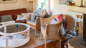 A cozy living room with a brown leather sofa, wicker chairs, a white coffee table, and a fireplace with decorative items. - 4 Person Holiday Home in Tyreso (Tyreso)
