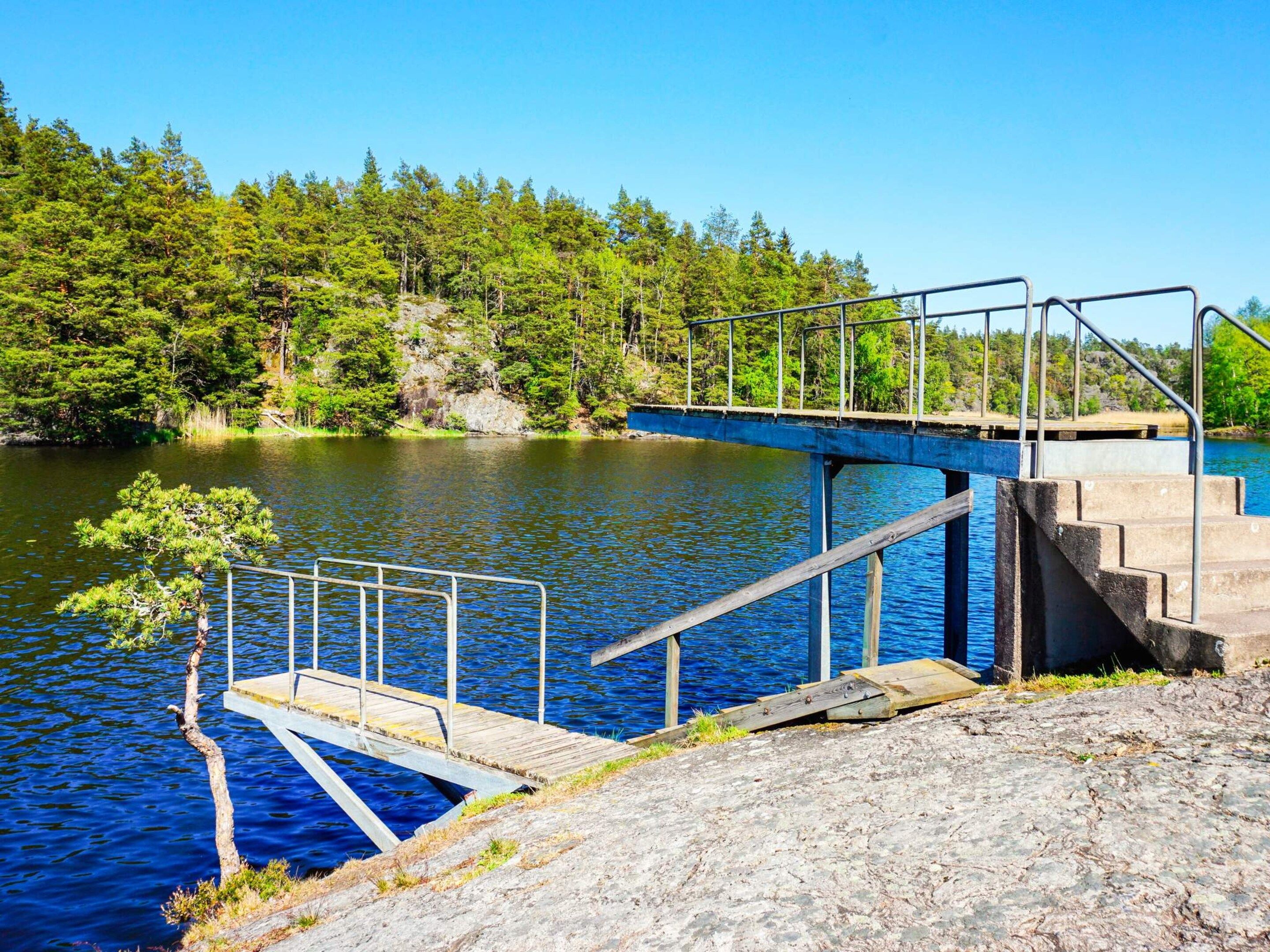A pier extending into a lake with a metal railing and steps leading down to the water.