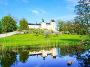 A large, white building with a symmetrical facade, a central tower, and a surrounding moat.