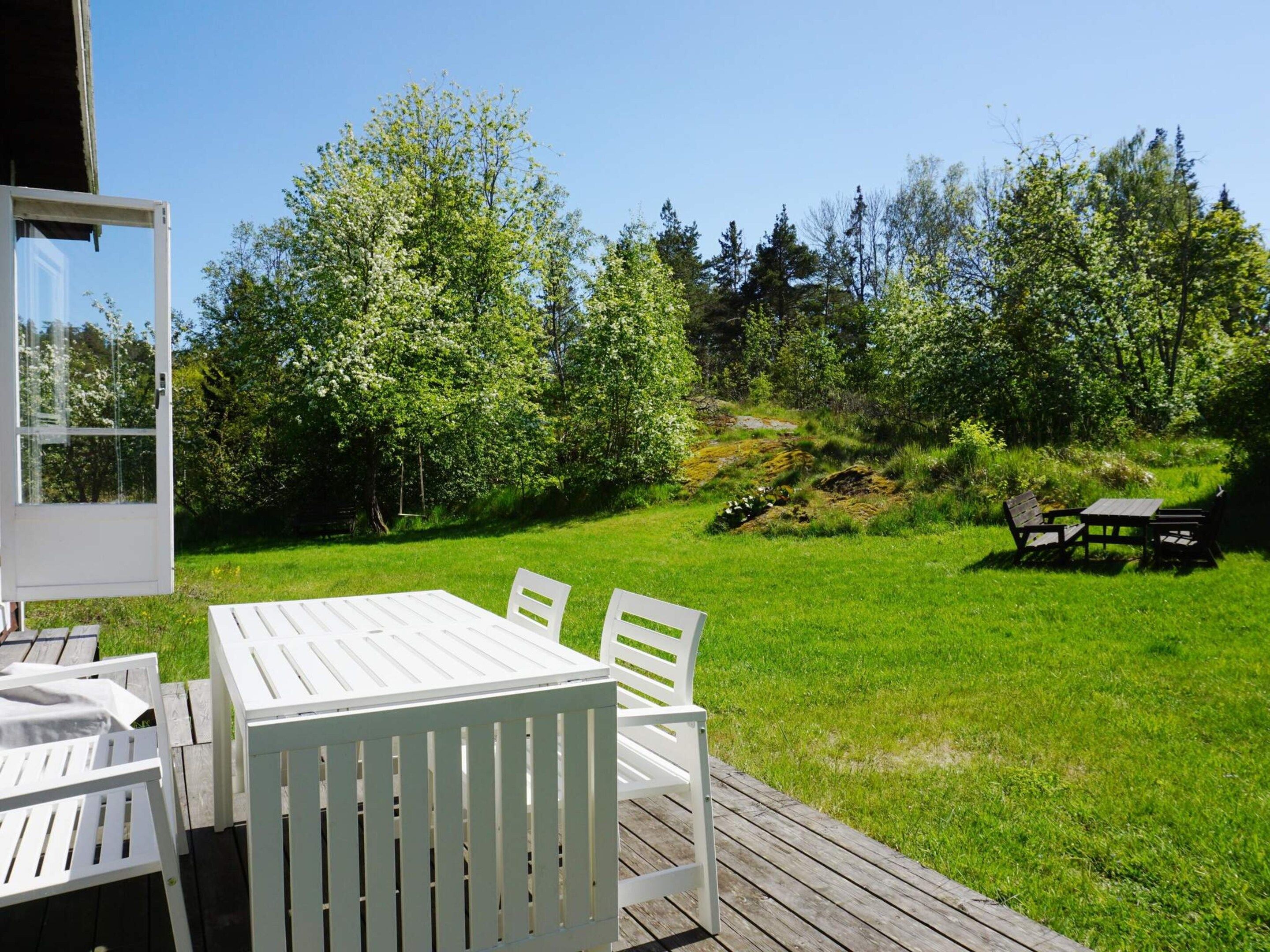 Eine Terrassenausstattung mit Tisch und Stühlen, umgeben von Rasen und Bäumen.