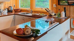 A modern kitchen with wooden cabinets, a large window, and a built-in stove. - 9 Person Holiday Home in Vesteroy (Hvaler)