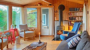 A cozy cabin interior with a fireplace, a sofa, a chair, a small table, and a bookshelf. - 9 Person Holiday Home in Vesteroy (Hvaler)
