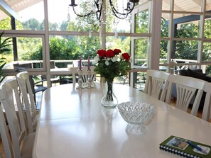 A dining area with a table, chairs, a vase with flowers, candles, and a notebook.