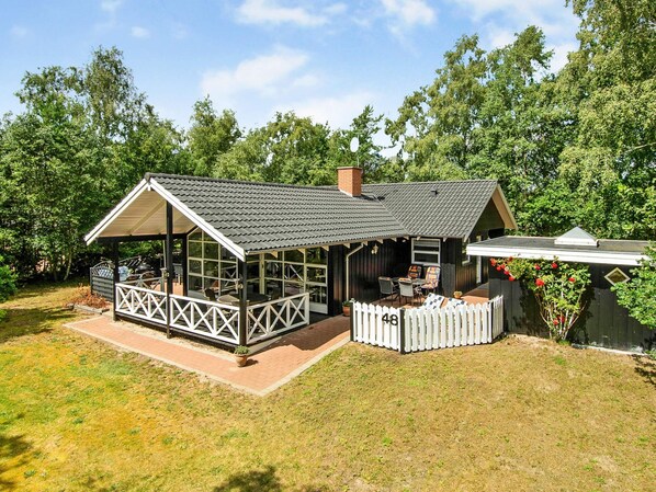 A wooden house with a covered porch and a fenced yard.