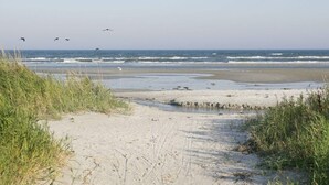 Un camí de sorra que porta a l'oceà, amb onades que brollen a la riba.