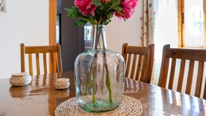 Un vase en verre transparent contenant des fleurs roses, posé sur une table en bois.