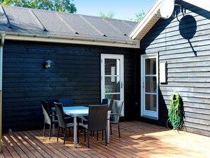 Een terras met een tafel, stoelen, een deur en een waterslang.