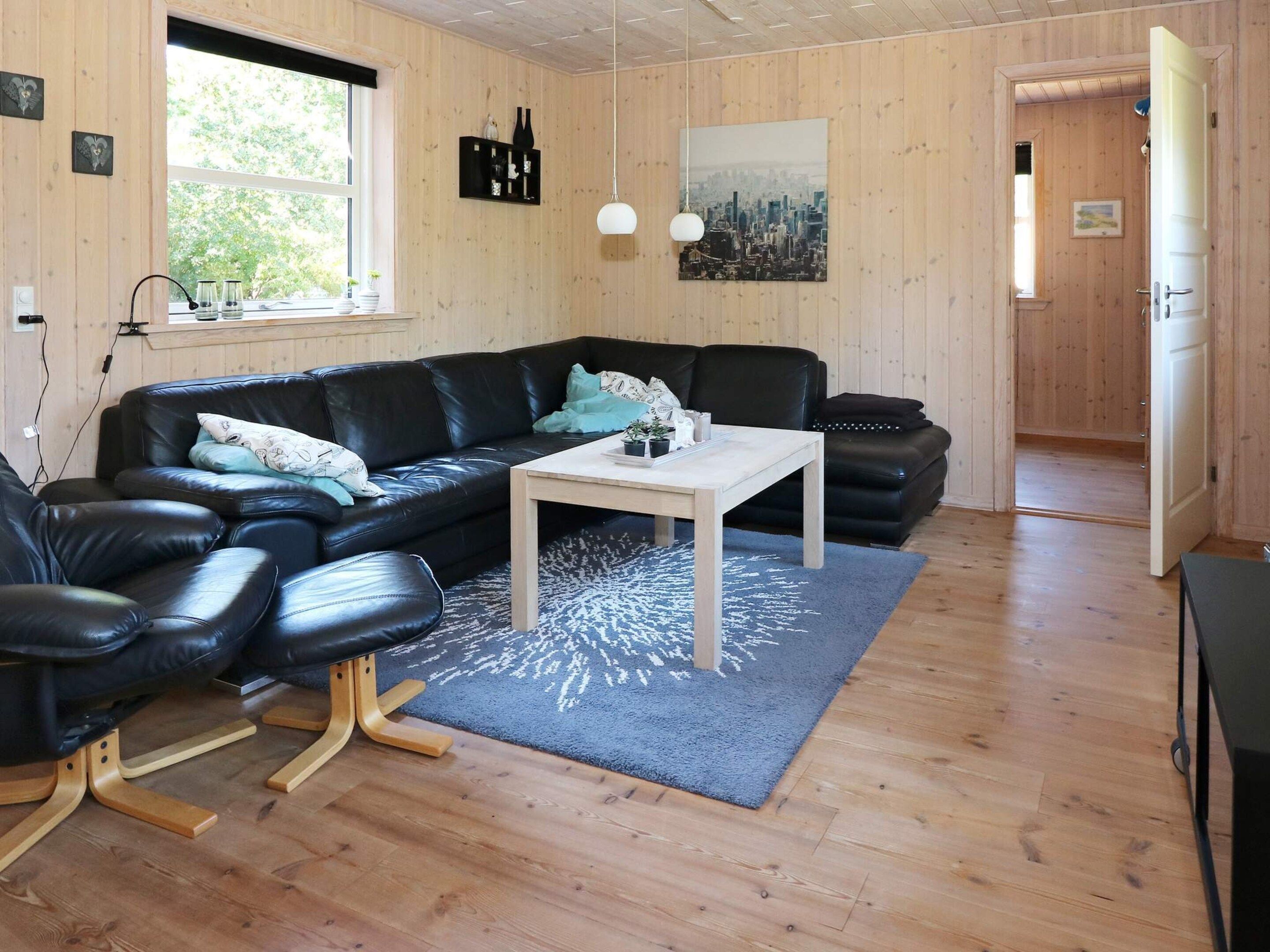A modern living room with a black leather sofa, a wooden coffee table, and a cityscape painting on the wall.