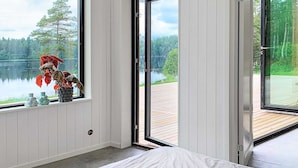 Una camera da letto con una grande finestra, un letto e vista su un lago e una foresta.