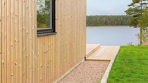 Un edificio moderno in legno con un'ampia finestra che si affaccia su un lago.