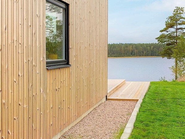A modern wooden building with a large window overlooking a lake.