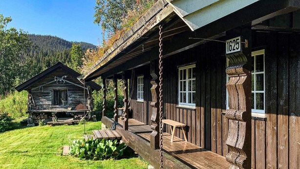En rustik træhytte med veranda, et lille bord og en bænk.