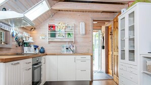 Eine Küche mit Holzausstattung, einem Einbauofen und einem Spülbecken mit dekorativer Rückwand.
