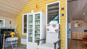 Ein gemütliches Zimmer mit einem Holzstuhl, einer Vitrine und einem kleinen Tisch mit einer Lampe.