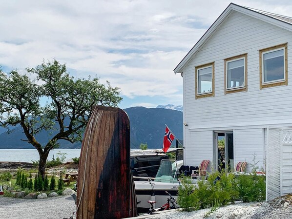 A white house with a dock, a boat, and a flag. - 5 Person Holiday Home in Torrvikbygd (Kvam)