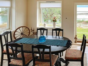 A dining area with a round table, chairs, a decorative wheel, and a vase with flowers. - 5 Person Holiday Home in Torrvikbygd (Kvam)