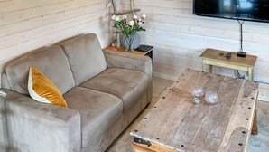 A living room with a sofa, a coffee table, a TV mounted on the wall, and a wooden ladder. - 5 Person Holiday Home in Torrvikbygd (Kvam)
