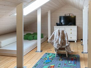 A loft bedroom with a sloped ceiling, a bed with green pillows, a white dresser, a television on top, and a colorful rug. - 5 Person Holiday Home in Torrvikbygd (Kvam)